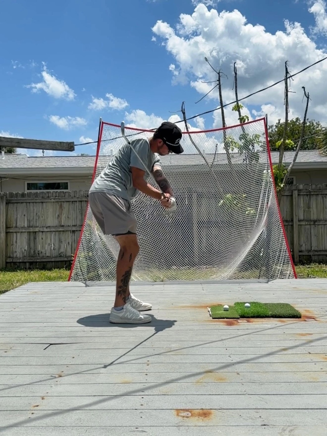 Kadin practicing his golf swing into a backyard net on a sunny day